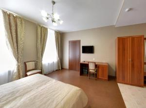 a bedroom with a bed and a desk and a tv at Aximaris furnished rooms in Saint Petersburg