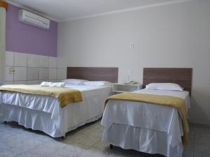 two beds are in a room with purple at Pousada da Pedra in Delmiro Gouveia