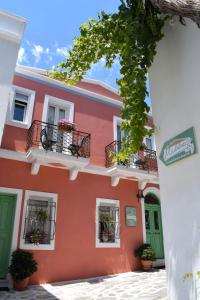 un edificio arancione con finestre e piante in vaso di Madalena's Family Rooms a Città di Tinos