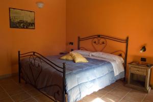 Ce lit se trouve dans une chambre dotée d'un mur orange. dans l'établissement La Casa nella Prateria, à Altomonte