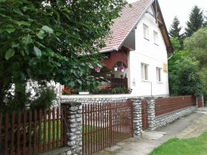 a white house with a fence and a gate at Czakó Vendégház és Nyaralóudvar in Szilvásvárad