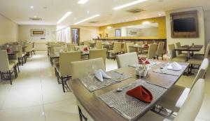 a restaurant with tables and chairs and a television at Nobile Suites Gran Lumni in Rio Branco