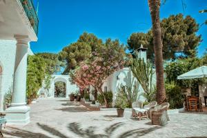 a patio with chairs and tables and trees at Masseria Il Frantoio in Ostuni