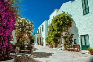a street in a town with white buildings and purple flowers at Masseria Il Frantoio in Ostuni