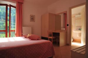 a bedroom with a bed and a desk and a window at Affittacamere B&B Trattoria della Posta in Maissana