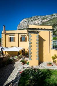 a yellow house with a mountain in the background at Agriturismo Antico Casale Colli Di San Pietro in Piano di Sorrento