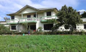 a large white house with a tree in front of it at Avon Field Holiday Bungalow in Nuwara Eliya