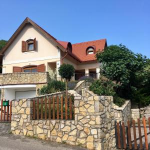 una casa con una pared de piedra y una valla en Nyugalom Szigete Vendégház SZIGLIGET, en Szigliget