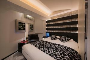 um quarto com uma cama preta e branca e uma cadeira em Hotel Water Resort Sendai (Adult Only) em Sendai