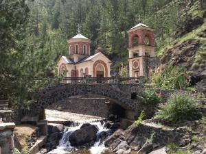 a bridge over a stream in front of a church at Apartment Bajka in Mokra Gora