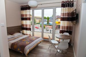 a bedroom with a bed and a balcony with a table and chairs at Holiday-Darłówko in Darłówko