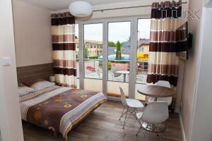 a bedroom with a bed and a balcony with a table and chairs at Holiday-Darłówko in Darlowko