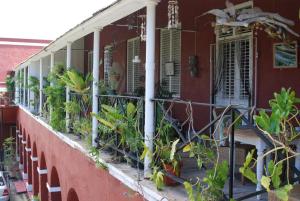 a red house with plants on a balcony at Charming Old World Apartment in Bridgetown