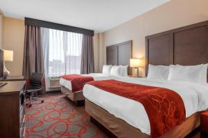 a hotel room with two beds and a desk at Comfort Inn & Suites near Stadium in Bronx +51 photos