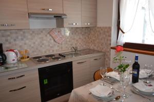 a kitchen with a sink and a table with wine glasses at Apartment Slavica in Kornić