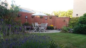 a patio with two chairs and an umbrella in a garden at Flint Lodge in Peacehaven