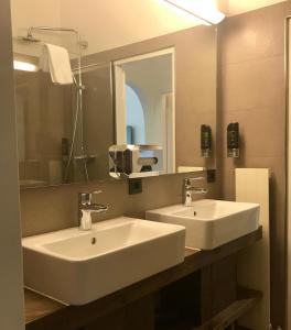 a bathroom with two white sinks and a mirror at Marmotta Alpin hotel in Mühlbach am Hochkönig