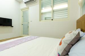 a white bedroom with a bed and a window at Smile Castle in Luodong