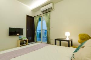 a bedroom with a bed and a television and a teddy bear at Smile Castle in Luodong