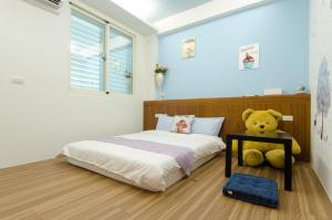 a bedroom with a teddy bear sitting next to a bed at Smile Castle in Luodong