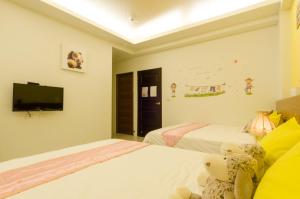 a bedroom with two beds and a tv on the wall at Smile Castle in Luodong
