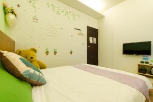 a teddy bear sitting on a bed in a bedroom at Smile Castle in Luodong +14 photos