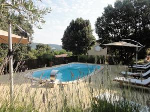 a swimming pool in a yard with chairs and an umbrella at Gîtes Les 3 Cigales in Vallon-Pont-dʼArc