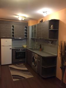 a kitchen with wooden cabinets and a sink and a dishwasher at Apartment Perushtiza 3 in Burgas