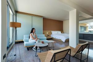 a woman sitting on a couch in a hotel room at Acropolis View Luxury Apartment in Athens