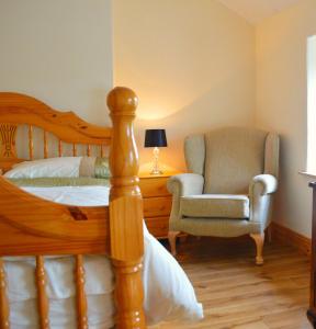 a bedroom with a bed and a chair at Biddys Cottage in Culdaff