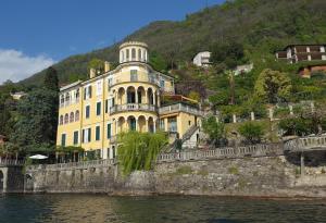 un edificio amarillo en una colina junto al agua en Villa Plinio Lago di Como, en Dervio