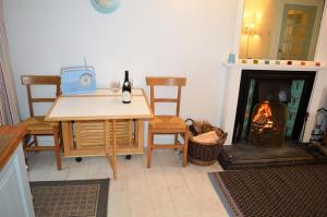 a room with a table and chairs and a fireplace at Newton Cottage North in Inveraray