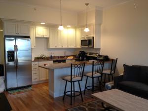 a kitchen with a refrigerator and two bar stools at Ocean Front condo in the heart of Hampton Beach in Hampton