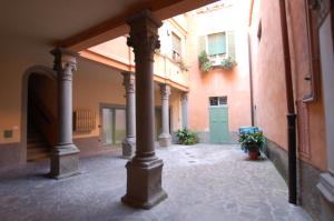 an empty courtyard with columns and a green door at La Rosa Scarlatta in Bergamo