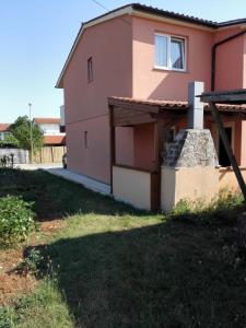a house with a grass yard in front of it at Apartment Kisic in Fažana
