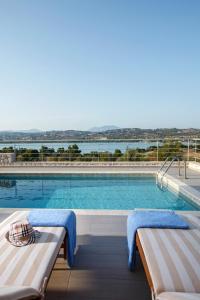 a large swimming pool with two benches in front of it at Edem Resort in Porto Heli