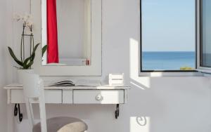a bathroom with a sink, mirror, and window at Iris Beach Hotel in Monemvasia
