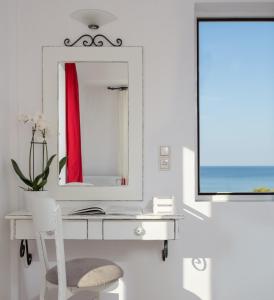 a mirror on the wall above a white sink at Iris Beach Hotel in Monemvasia
