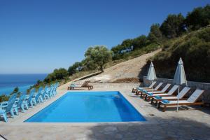a swimming pool with lounge chairs and the ocean at Myrtos View Apartments in Anomeriá