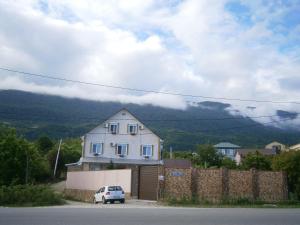 una casa blanca con un coche aparcado delante de ella en Guest house Barhatniy sezon en Novy Afon