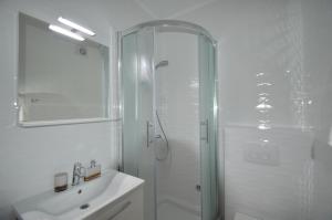 a white bathroom with a shower and a sink at Apartments Silvia in Zadar
