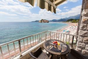 a balcony with a table and chairs and a beach at Apartments Lungo Mare in Sveti Stefan