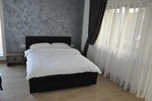 una camera da letto con letto con lenzuola e tende bianche di Yes Home a Călimăneşti