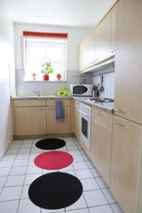 ハイデルベルクにあるCharlotte Flat Heidelbergの白いキャビネットと赤と黒のアクセントが特徴のキッチン