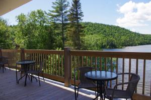a deck with tables and chairs and a view of a river at Auberge La Tanière in Tadoussac