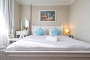 biała sypialnia z dużym białym łóżkiem z niebieskimi poduszkami w obiekcie Century Bay Private Residences w mieście Bayan Lepas