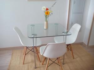 una mesa de cristal con sillas blancas y un jarrón de flores en New La Granada, en Granada