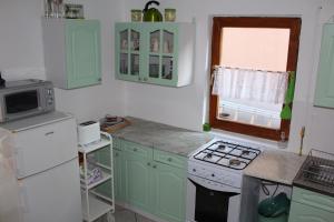 cocina con armarios verdes y nevera blanca en Dóra Apartman, en Balatongyörök