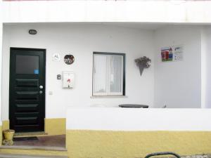 una pared blanca con una puerta negra y una ventana en Alojamento Tiago & Jorge Guesthouse, en Nazaré