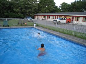 een man zwemmend in een zwembad bij Motel Des Erables in Coteau-du-Lac